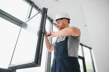 handsome young man installing bay window in new house construction site