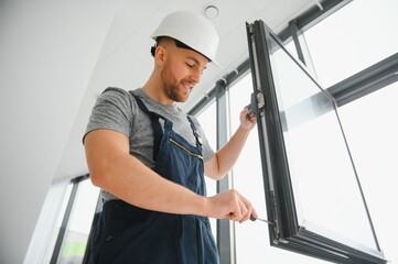 Construction worker repairing plastic window with screwdriver indoors, space for text. Banner design