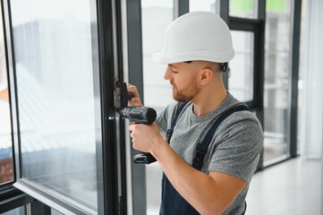Construction worker using drill while installing window indoors