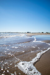 Agua y olas de playa en día soleado llegan a la arena.