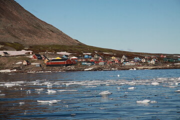 niewielka osada u wybrzeży grenlandii i pokryte topniejącym lodem morze w porze letniej
