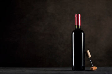 Fototapeta na wymiar Red Wine bottle and corkscrew on a dark background with copy space
