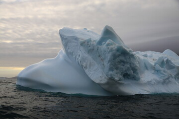 masywne bloki lodowe na morzu o zachodzie słońca - 482908801