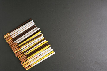 Cereal straw in multi-colored glaze lies in a row on a dark surface