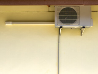 The compact air compressor unit is hanging on the yellow wall of the countryside house.
