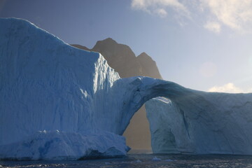 ogromna góra lodowa w kształcie łuku dryfująca u wybrzeży grenlandii - obrazy, fototapety, plakaty