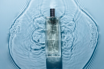 Perfume bottle on blue water wavy background. Fresh sea fragrance concept. Pure and chilly.