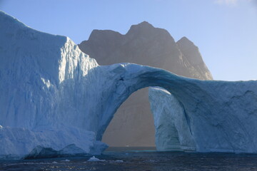 ogromna góra lodowa w kształcie łuku dryfująca u wybrzeży grenlandii
