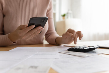 Close up woman working makes calculations on calculator, pay bills through online e-bank...