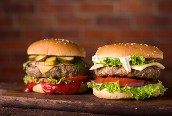 Fresh burgers on wooden table and brick wall background