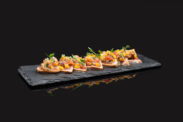 Sushi rolls set served on black stone slate on dark background