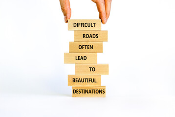 Motivational symbol. Blocks with words Difficult roads often lead to beautiful destinations. Beautiful white background, copy space. Businessman hand. Business, psychology and motivational concept.