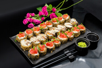 Sushi rolls set served on black stone slate on dark background