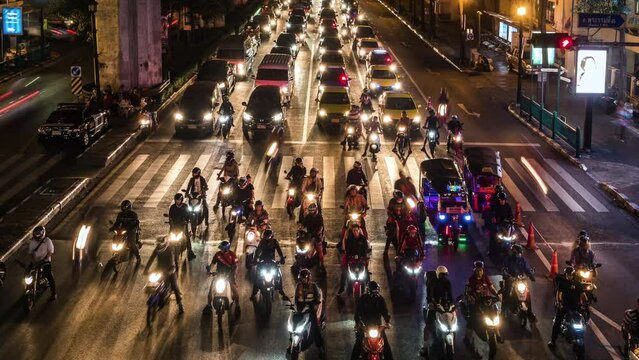 Timelapse view of rush hour traffic at busy intersection in Bangkok, Thailand. Motorcycles, scooters and mopeds are popular modes of transportation in Thailand, Vietnam and many other Asian countries.