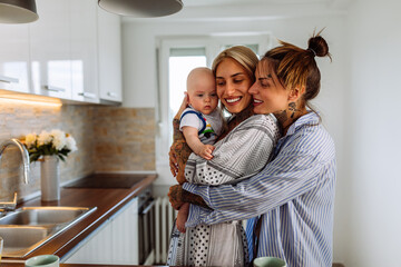 Two lesbian women with a baby boy at home - obrazy, fototapety, plakaty