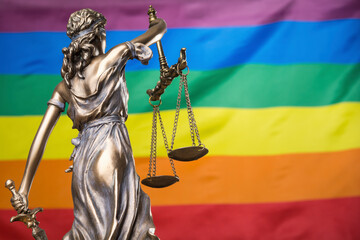 The blindfolded goddess of justice Themis or Justitia against the rainbow flag of LGBT community,...