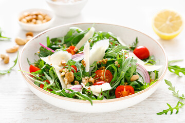 Fresh vegetable salad with arugula, tomato, onion, parmesan cheese and cashew nuts