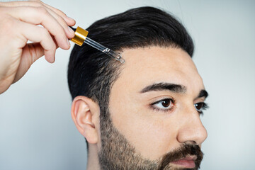 Man baldness treatment. Nature hair care procedure. Oil drop at scalp. Male person applying...