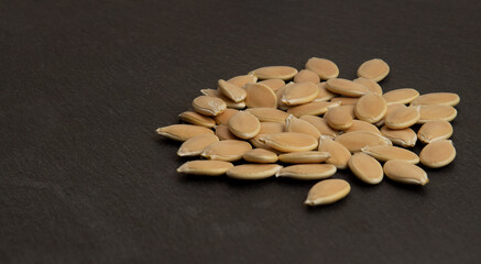 Fototapeta na wymiar unpeeled pumpkin seeds piled in a pile on a dark surface
