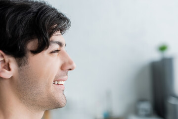 profile of happy brunette man on blurred background.