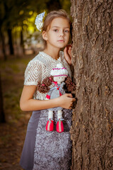 Charming little girl in forest with doll