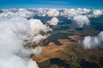 Obraz premium Aerial view from high altitude of earth covered with white puffy cumulus clouds on sunny day