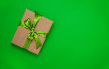 Gift box with green ribbon and bow on green background background.
