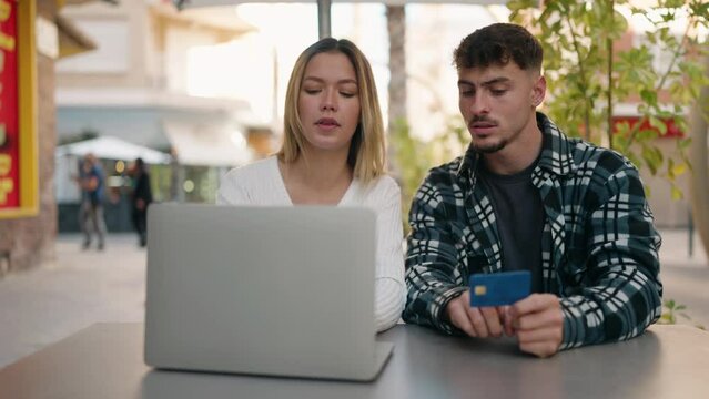 Young couple smiling confident using laptop and credit card at coffee shop terrace
