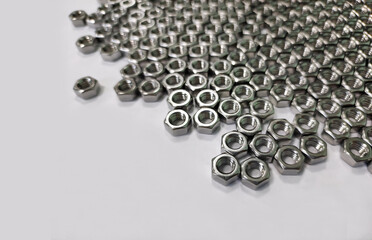a large number of metal nuts scattered on a white background with blurred edges