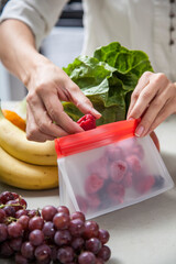 A woman packs fresh fruit, vegetables and food into clear storage bags