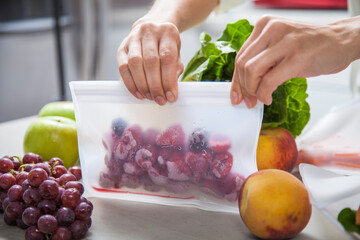 A woman packs fresh fruit, vegetables and food into clear storage bags