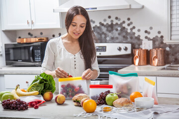 A woman packs fresh fruit, vegetables and food into clear storage bags
