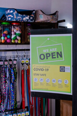 sign with the phrase "we are open" and instructions to be safe and careful of covid-19 in a local retail business -  petshop