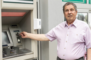 Senior man inserting credit card to ATM