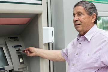 Naklejka na ściany i meble Senior man inserting credit card to ATM