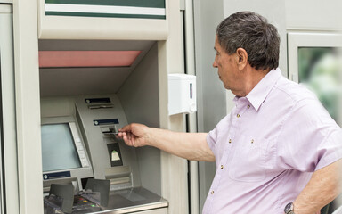 Obraz na płótnie Canvas Senior man inserting credit card to ATM