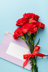 red carnation and pink paper envelope with space for text on blue background, top view, holiday background, postcard Defender of the Fatherland Day, Women's Day, March 8, Mother's Day