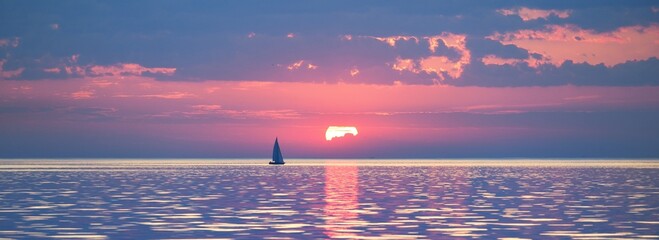 Baltic sea at sunset. Clear sky, blue and pink glowing clouds, soft golden sunlight. Water surface...