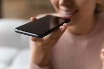 Close up female hand holds smartphone near mouth using speakerphone, send audio voice message to...