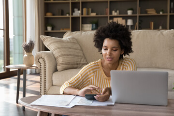African woman makes calculations on calculator pay utility bills, loan via e-bank application on...