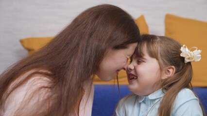 Cheerful girl daughter plays with her nose with her mother at home, happy family. Happy family...