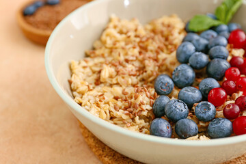 Bowl with healthy oatmeal and berries on table, closeup