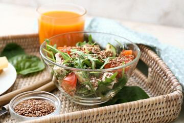 Bowl with healthy vegetable salad and flax seeds on tray