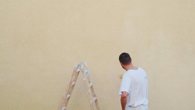 Painter man painting a wall with a roller. Home renovations