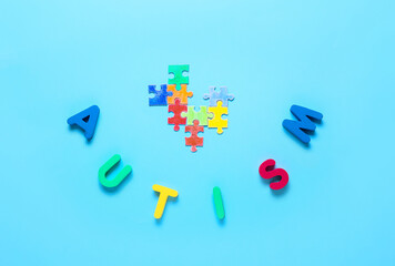Word AUTISM with colorful puzzle pieces on color background