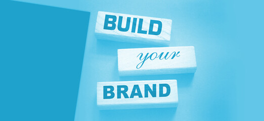 Phrase BUILD YOUR BRAND written on wooden blocks. With vintage styled background. Branding...
