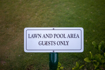 Warning sign warns tourists and visitors to stay out of lawn and pool area guests only