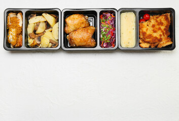Lunch boxes with different delicious food on light background