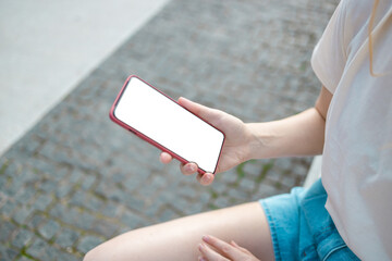 Woman hand using her mobile phone, reading messages on mobile phone in a city park