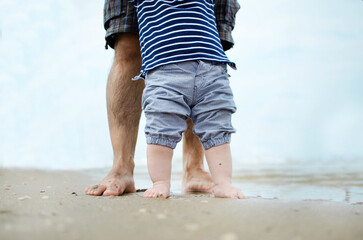 Father and son walking by the ocean - obrazy, fototapety, plakaty